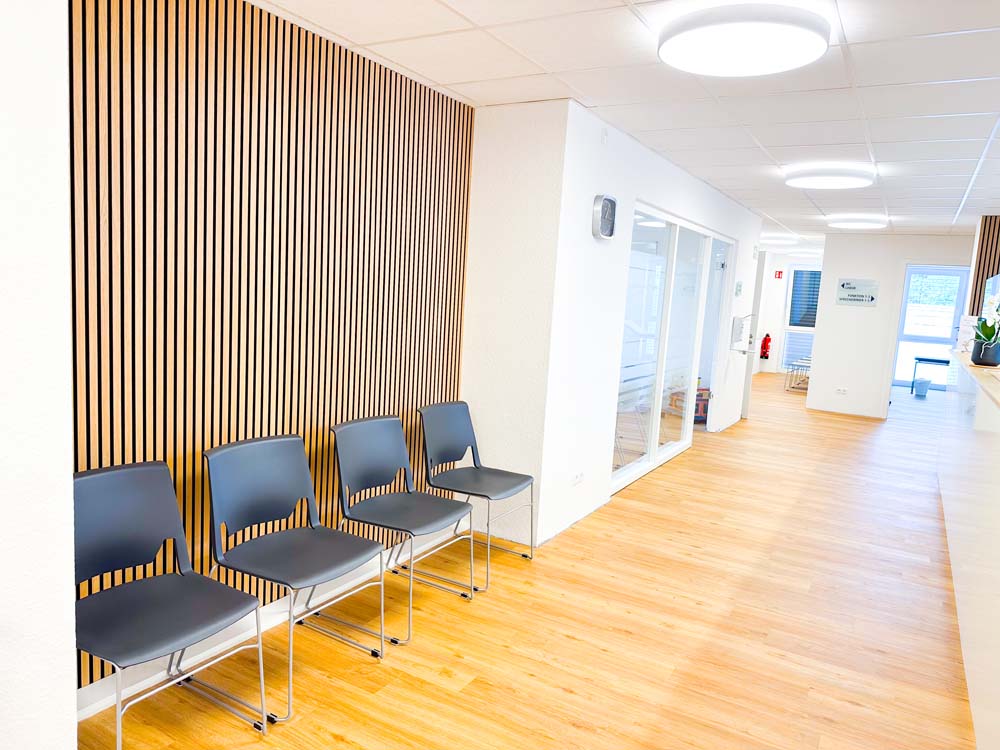 Praxisflur mit Wartebereich und Wandapplikation aus Holz.