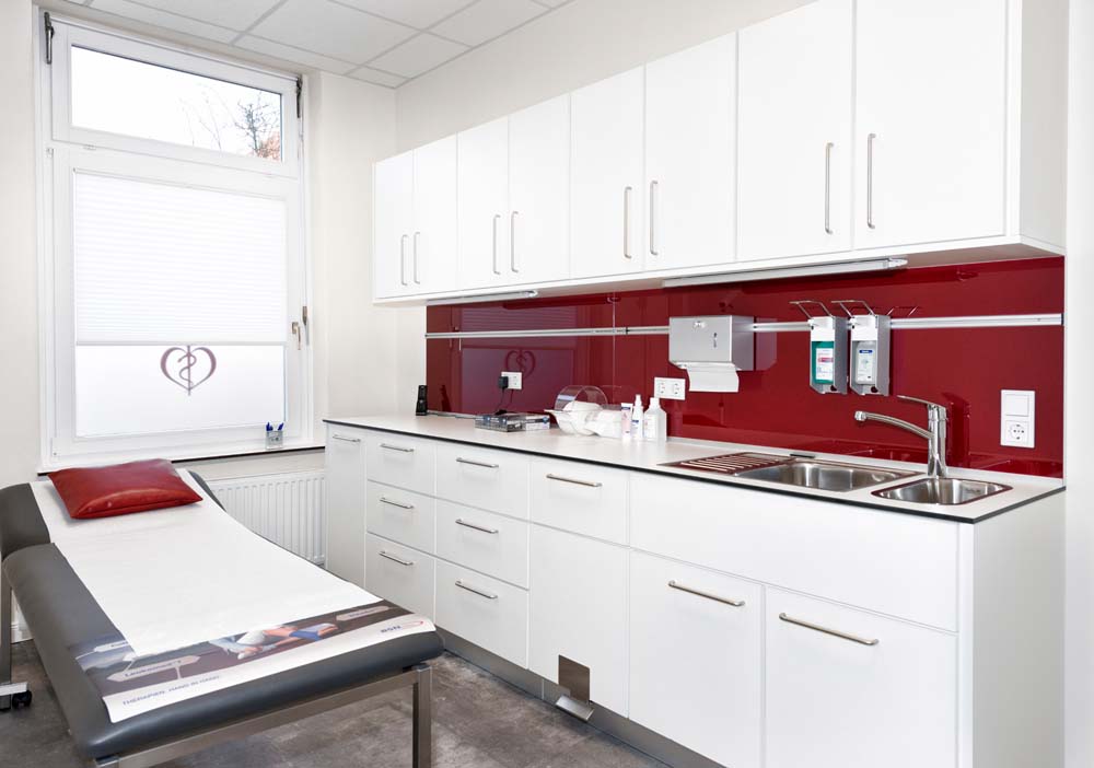 Behandlungszimmer einer Arztpraxis mit großer funktionaler Schrankwand samt integrierter Spüle.